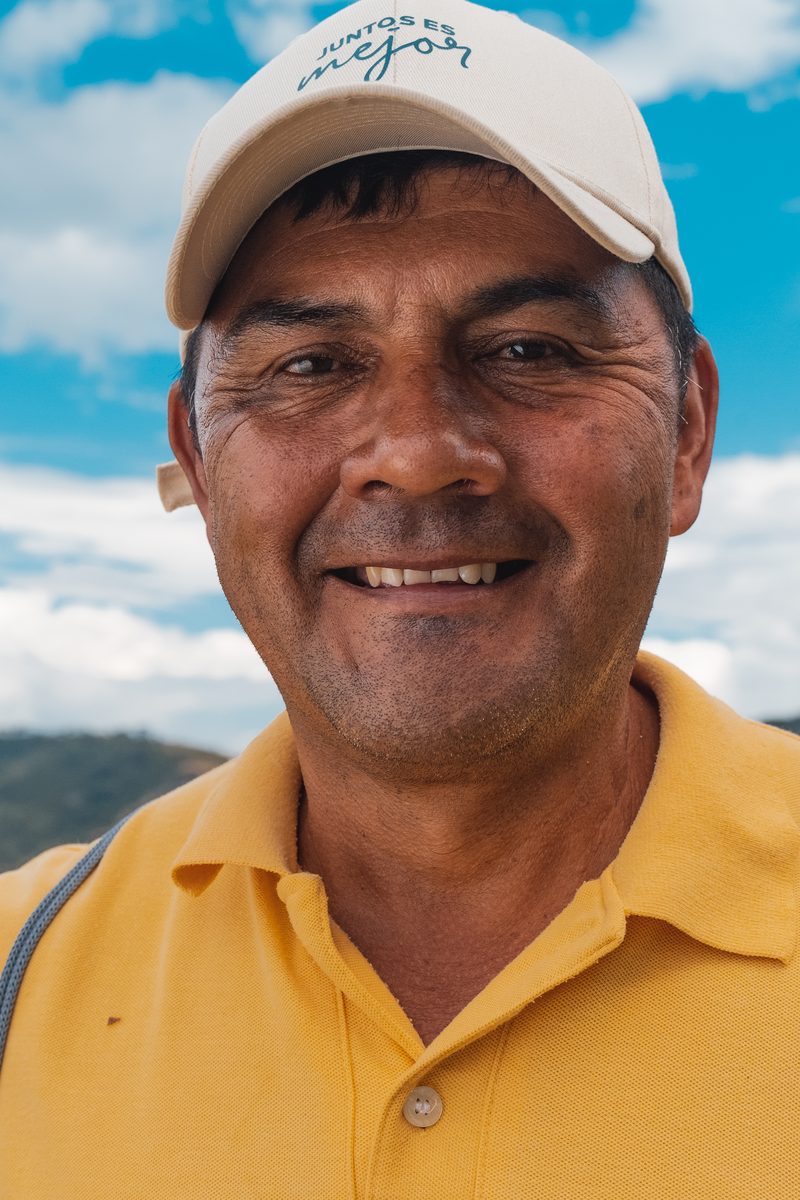 A coffee grower in the program on his own farm, the Andean range behind him