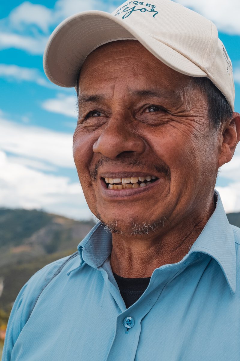 A coffee grower in the program on his own farm, a palm behind him