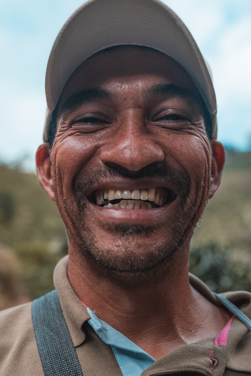 A coffee grower in the program laughing, the slope of his farm behind him